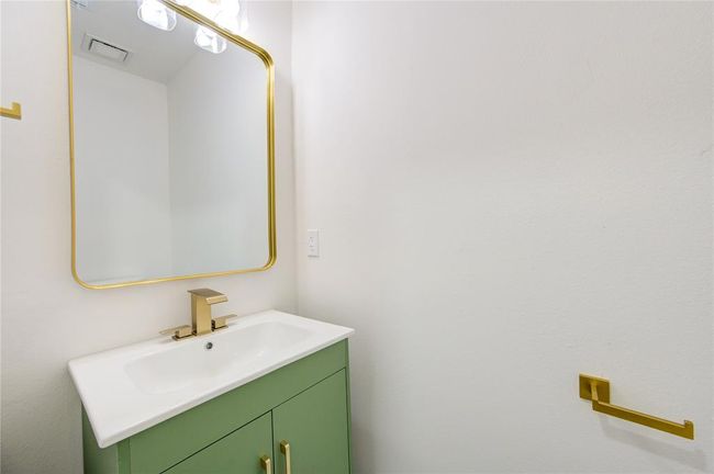 The powder room is a beautifully designed space featuring a trendy green vanity cabinet, adding a bold and modern touch to the home’s aesthetic. | Image 26