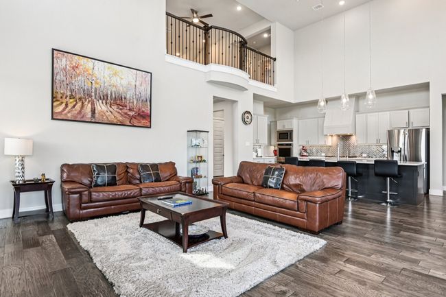 Living room featuring dark wood finished floors, a high ceiling, a ceiling fan, and recessed lighting | Image 9