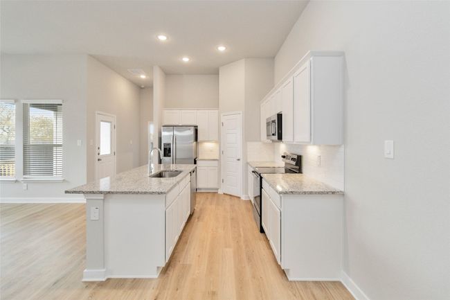 Kitchen with tasteful backsplash, a center island with sink, appliances with stainless steel finishes, light wood-type flooring, and a sink | Image 14
