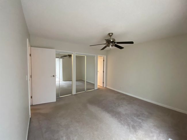 Unfurnished bedroom with a ceiling fan, baseboards, multiple closets, and carpet | Image 9