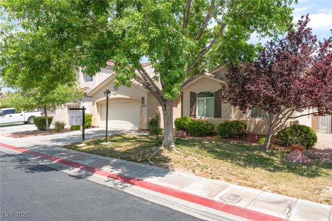 Obstructed view of property featuring driveway, stucco siding, an attached garage, and a front lawn | Image 6