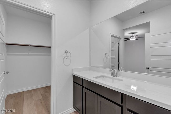 Bathroom with vanity, wood finished floors, a ceiling fan, a spacious closet, and baseboards | Image 18