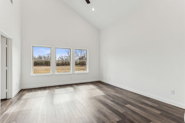 Unfurnished bedroom featuring high vaulted ceiling, dark wood-type flooring, and a ceiling fan | Image 28
