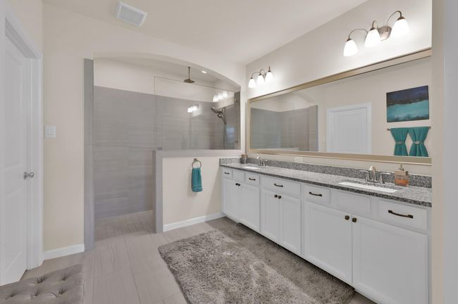 The primary bathroom features a generously sized shower with dual shower heads. The rain head will have you feeling like you're in a spa retreat. Granite countertops, dual sinks, plentiful cabinetry, and stylish fixtures all around... this is the bathroom you deserve! | Image 17