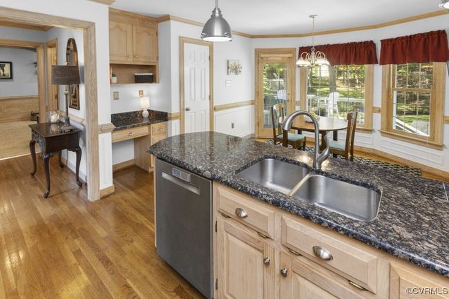 Kitchen with stainless steel dishwasher, a sink, light brown cabinets, light wood-type flooring, and a wainscoted wall | Image 10