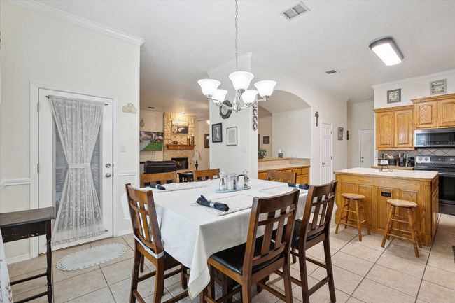 Dining space featuring light tile patterned floors, a chandelier, ornamental molding, and arched walkways | Image 13