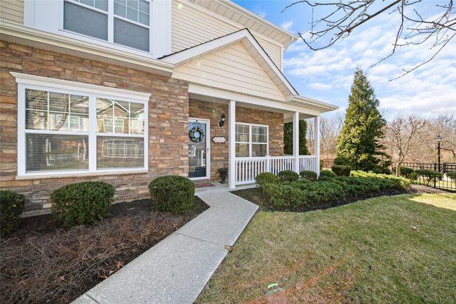 Doorway to property featuring stone siding, a lawn, and covered porch | Image 22
