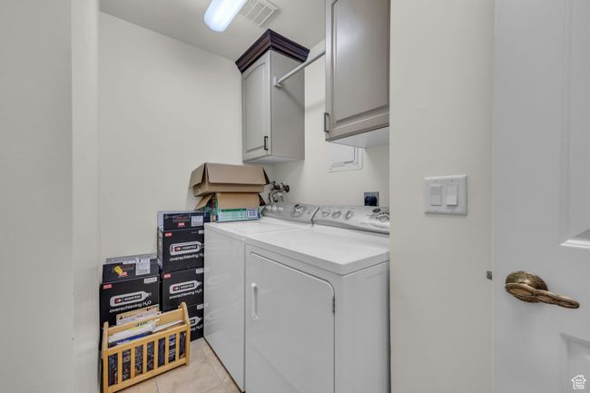 Washroom with cabinet space, visible vents, washing machine and clothes dryer, and light tile patterned floors | Image 16