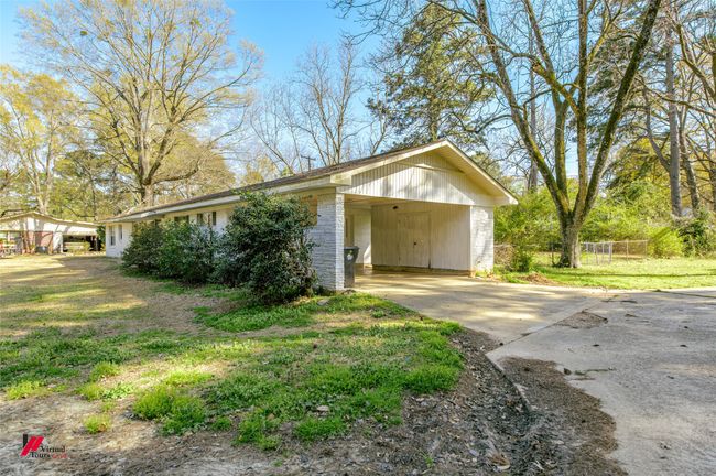 Garage with concrete driveway, a carport, and fence | Image 23