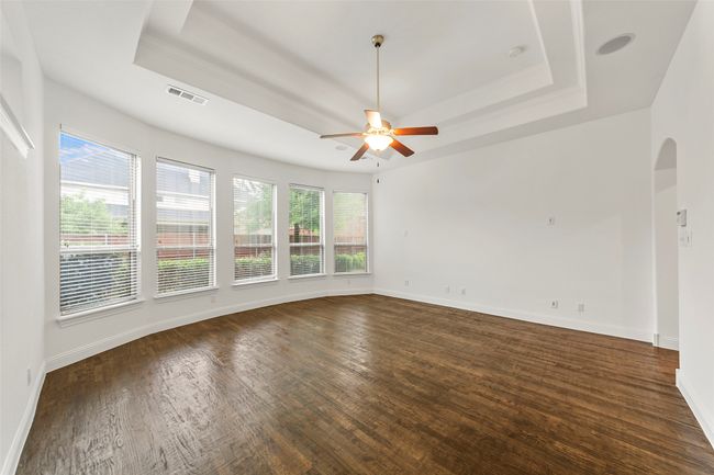 Empty room with a ceiling fan, a tray ceiling, visible vents, and dark wood finished floors | Image 17