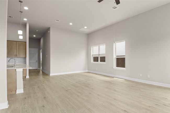 Unfurnished living room with ceiling fan, light wood-style floors, recessed lighting, baseboards, and a sink | Image 11