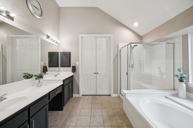 The ensuite bath includes double sinks, a large framed mirror, and a walk-in shower—providing both function and comfort in a clean, modern layout. | Image 19