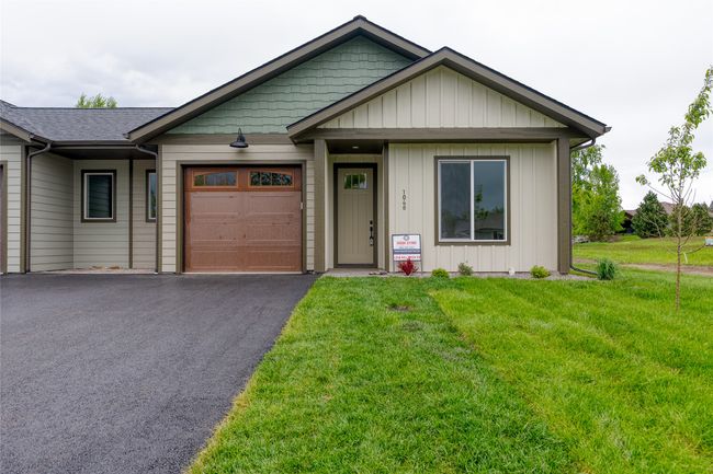 View of front of house with an attached garage, asphalt driveway, a front lawn, and board and batten siding | Image 33