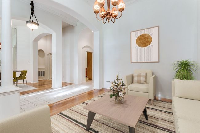 Living area with arched walkways, a chandelier, wood finished floors, and a towering ceiling | Image 4