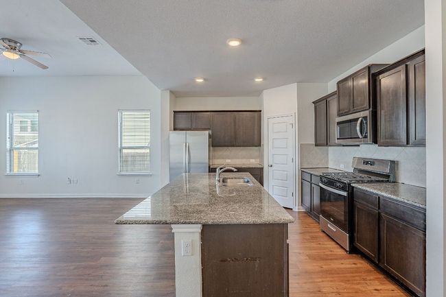 Kitchen with a sink, dark brown cabinetry, appliances with stainless steel finishes, and visible vents | Image 4