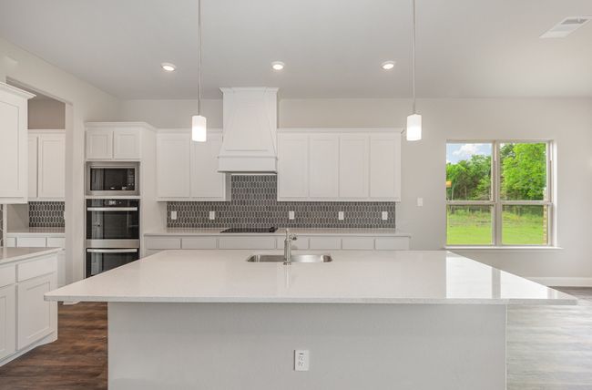 Kitchen featuring premium range hood, stainless steel appliances, tasteful backsplash, a sink, and white cabinets | Image 9