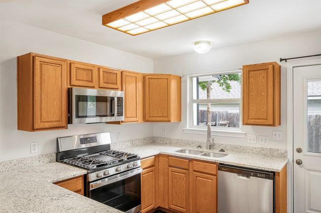 Kitchen with appliances with stainless steel finishes, light stone countertops, and brown cabinetry | Image 11