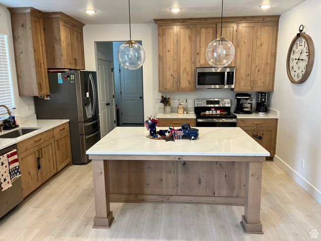 Kitchen featuring stainless steel appliances, a sink, light wood finished floors, decorative light fixtures, and recessed lighting | Image 6