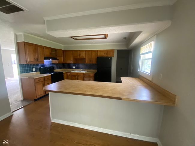 kitchen with a sink, black appliances, visible vents, a peninsula, and light countertops | Image 7