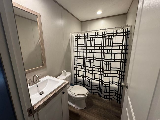 Full bath featuring wood finished floors, a shower with curtain, vanity, and crown molding | Image 15