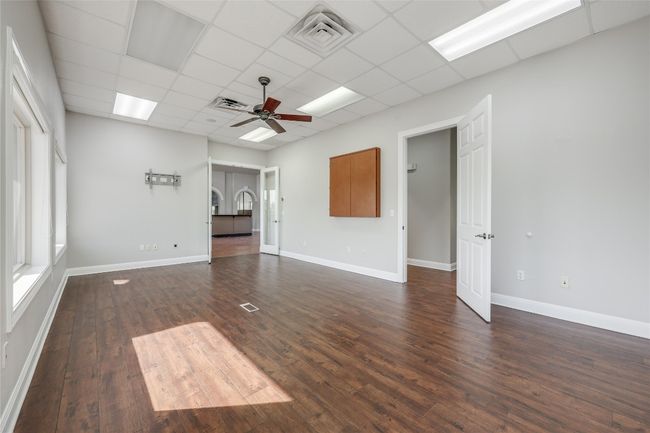 Unfurnished living room with dark wood finished floors, visible vents, a ceiling fan, and a drop ceiling | Image 13