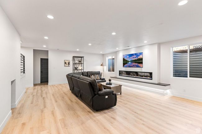 Living room featuring light wood-style floors, baseboards, a glass covered fireplace, and recessed lighting | Image 38