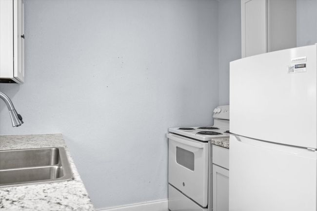 Kitchen with white appliances, a sink, light countertops, and baseboards | Image 7