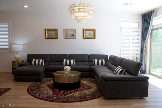 Living room with wood finished floors, plenty of natural light, and a chandelier | Image 11