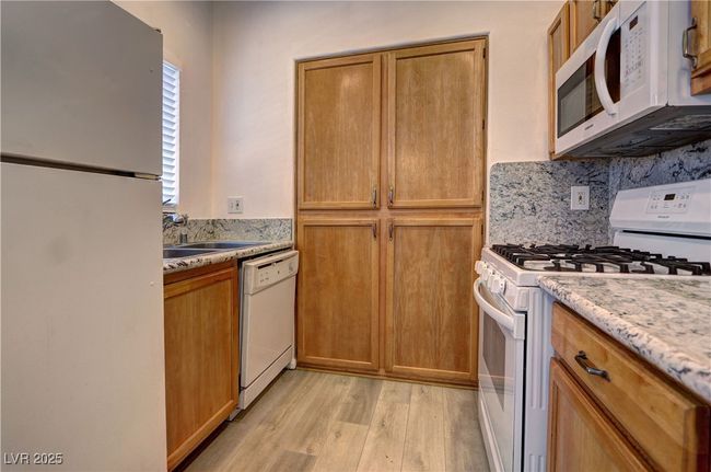 Kitchen featuring white appliances, a sink, light wood-style floors, brown cabinets, and​​‌​​​​‌​​‌‌​‌‌​​​‌‌​​‌‌​‌​​​​​‌ backsplash | Image 8