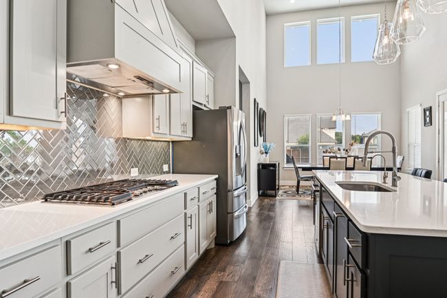 Kitchen with ventilation hood, appliances with stainless steel finishes, a chandelier, healthy amount of natural light, and a high ceiling | Image 12