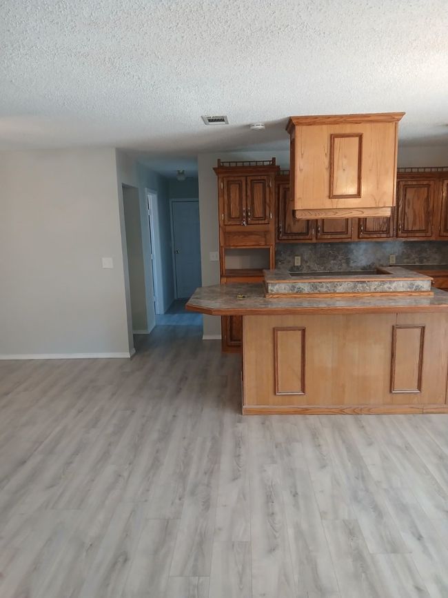 Kitchen with tasteful backsplash, a kitchen bar, a textured ceiling, and light wood-type flooring | Image 9