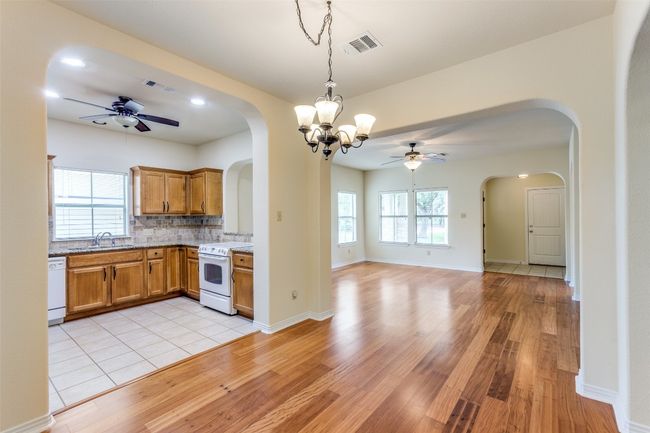 Kitchen featuring white appliances, ceiling fan, brown cabinetry, light wood-style flooring, and arched walkways | Image 11