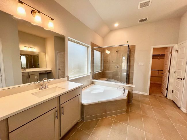 Full bath featuring a stall shower, a walk in closet, a bath, light tile patterned floors, and vanity | Image 13
