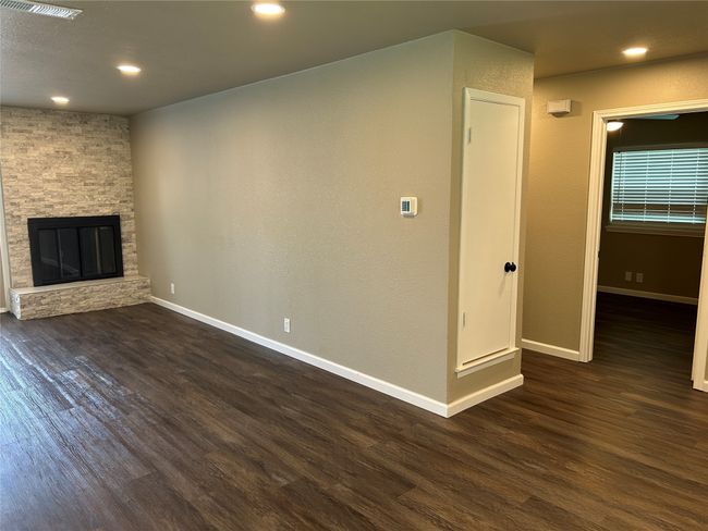 Unfurnished living room with dark wood-style flooring, baseboards, recessed lighting, and a stone fireplace | Image 13