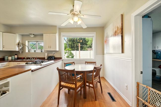Dining room with light wood-type flooring, a wainscoted wall, and ceiling fan | Image 8