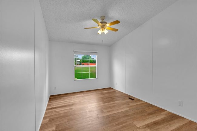 Empty room featuring ceiling fan, a textured ceiling, and wood finished floors | Image 22