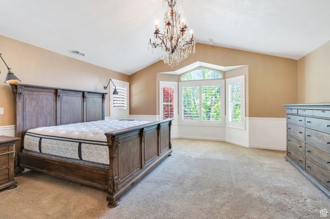 Bedroom with a chandelier, light carpet, vaulted ceiling, and baseboards | Image 25