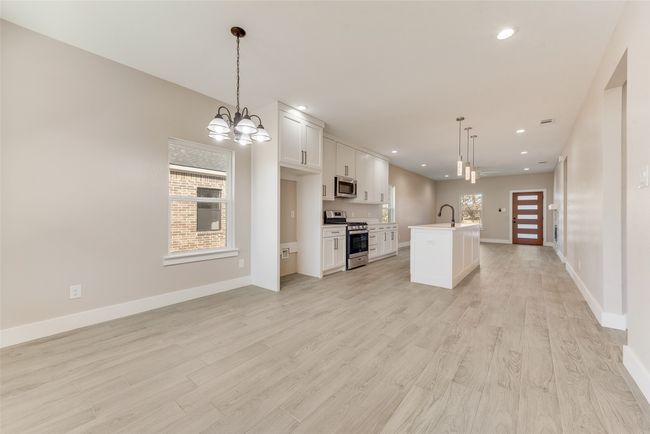 Kitchen with appliances with stainless steel finishes, open floor plan, a chandelier, white cabinets, and recessed lighting | Image 9