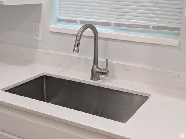 Kitchen view of a sink and light quartz counters | Image 8