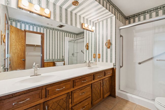Full bath with a shower stall, double vanity, wallpapered walls, and tile patterned flooring | Image 21