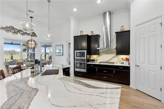 Kitchen featuring a sink, appliances with stainless steel finishes, crown molding, and wall chimney range hood | Image 37