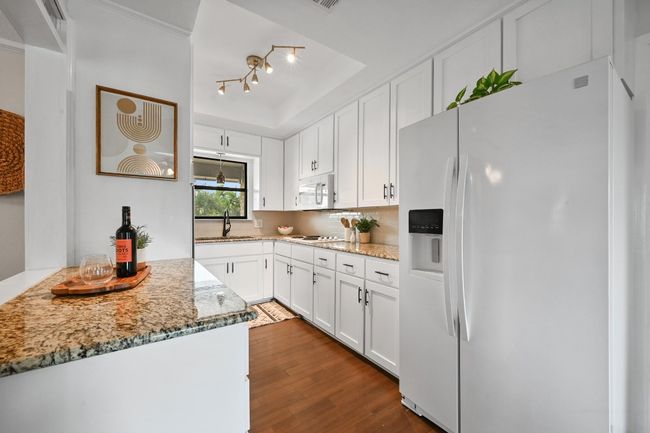 Kitchen featuring white appliances, a sink, white cabinets, and light stone counters | Image 9
