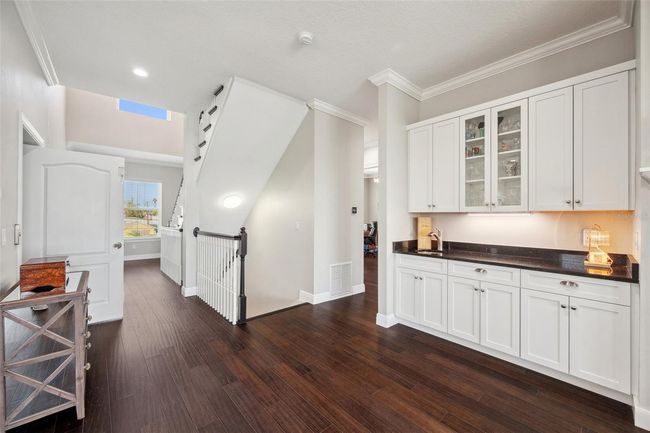 View of wet bar with black granite countertop and custom solid wood cabinetry. | Image 36
