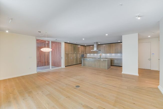 Kitchen featuring wall chimney exhaust hood, light wood-type flooring, open floor plan, recessed lighting, and an island with sink | Image 5
