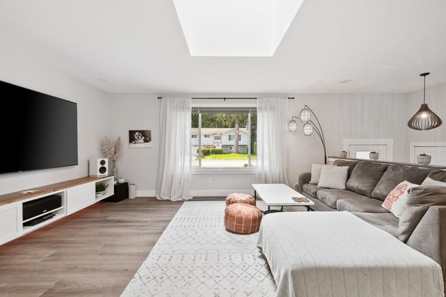 Living room featuring light wood-type flooring, baseboards, and a skylight | Image 16