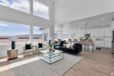 Living room featuring a high ceiling, light hardwood / wood-style floors, and a chandelier | Image 3