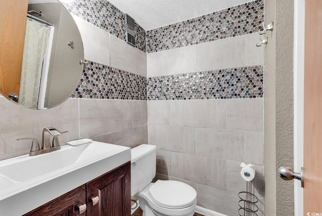 Full bath featuring tile walls, a textured ceiling, toilet, vanity, and a shower with curtain | Image 9
