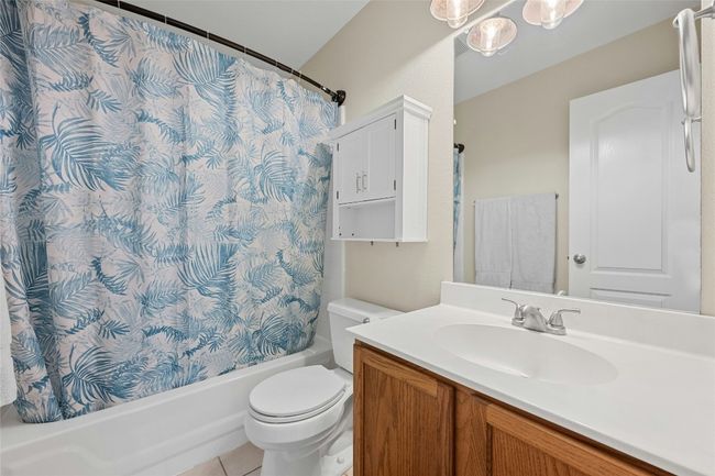 Full guest bath with toilet, tile patterned flooring, shower / bath combo with shower curtain, and vanity | Image 14