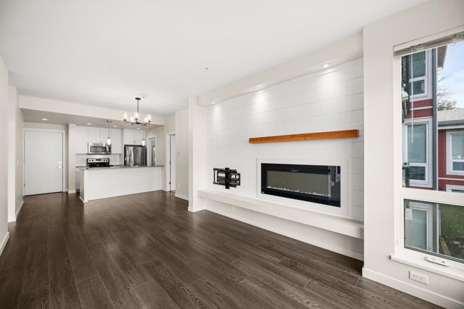 Unfurnished living room featuring a chandelier, a glass covered fireplace, dark wood-style flooring, and recessed lighting | Image 9