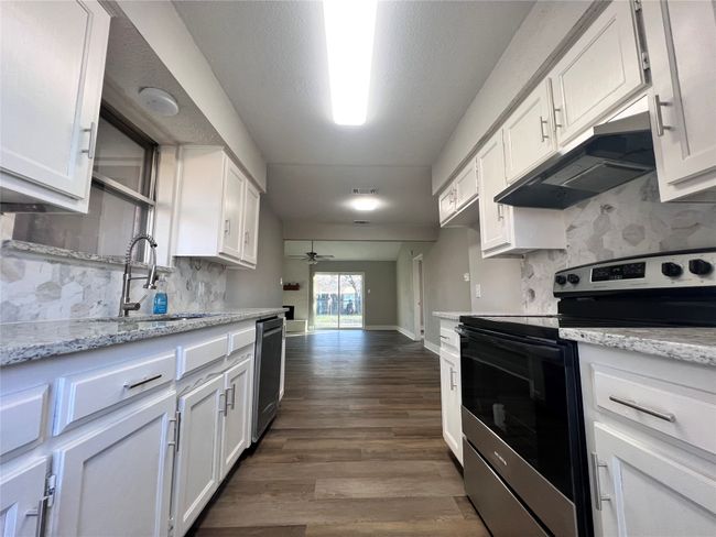 Kitchen with ceiling fan, sink, stainless steel appliances, white cabinets, and light stone counters | Image 10